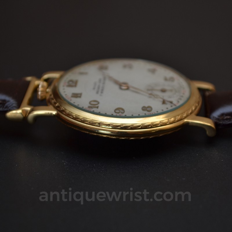 Rolex 1920s trench watch side profile, gold-plated case with guilloche bezel and crown detail on brown leather strap
