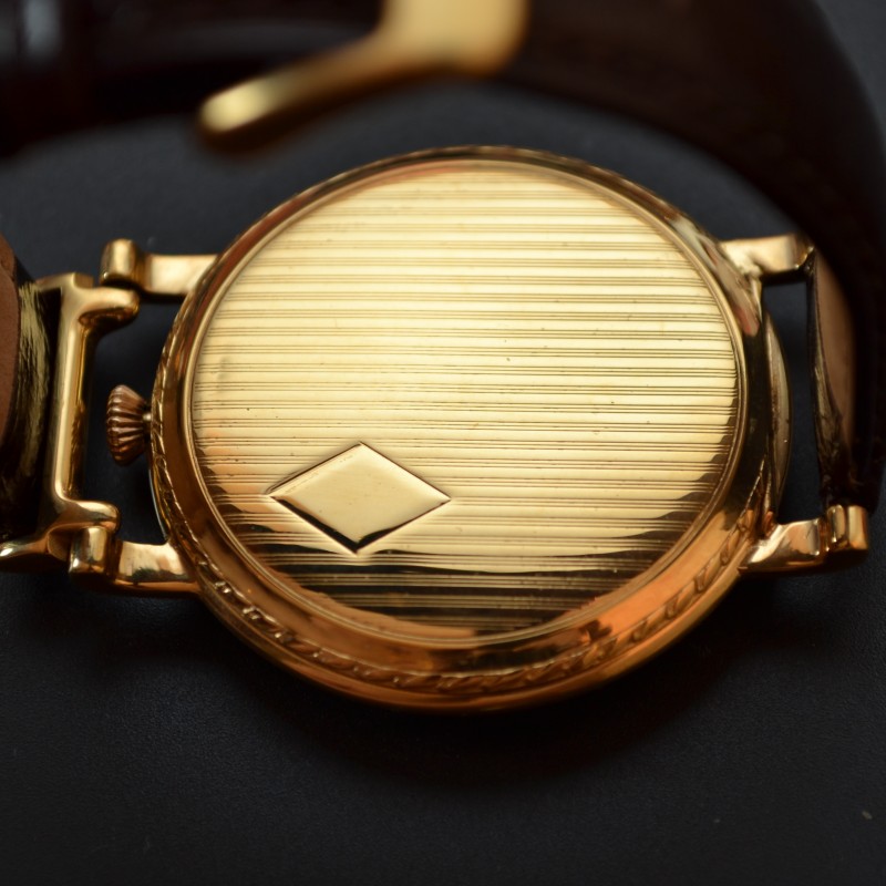 Rolex 1920s trench watch case back with horizontal guilloche engraving and gold-plated hinged expansible lugs