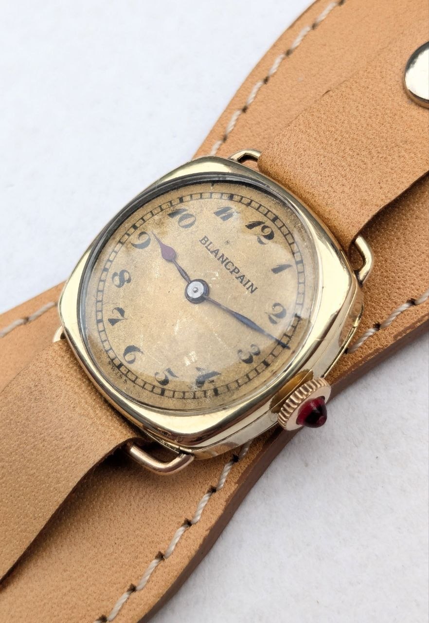 Close‑up of the dial: Blancpain‑LeCoultre trench watch, blued hands, guilloché pattern, and ruby crown visible