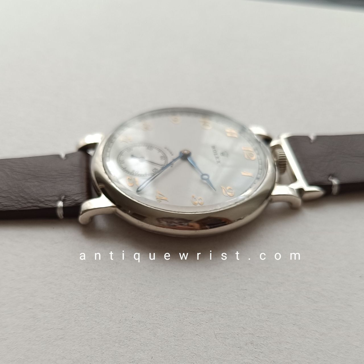 Close-up of a 1940s pocket-style Rolex wristwatch dial featuring gilt hour markers, cathedral-style blue hands, and a subtle aged patina on the beige surface.