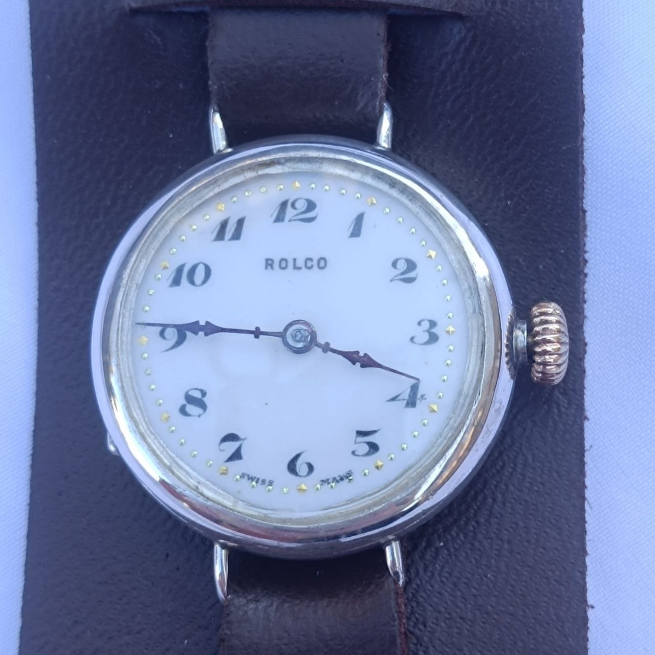 Antique 1916 Rolex Rolco trench watch with white porcelain dial, large Arabic numerals, and blued steel hands on a vintage leather strap.