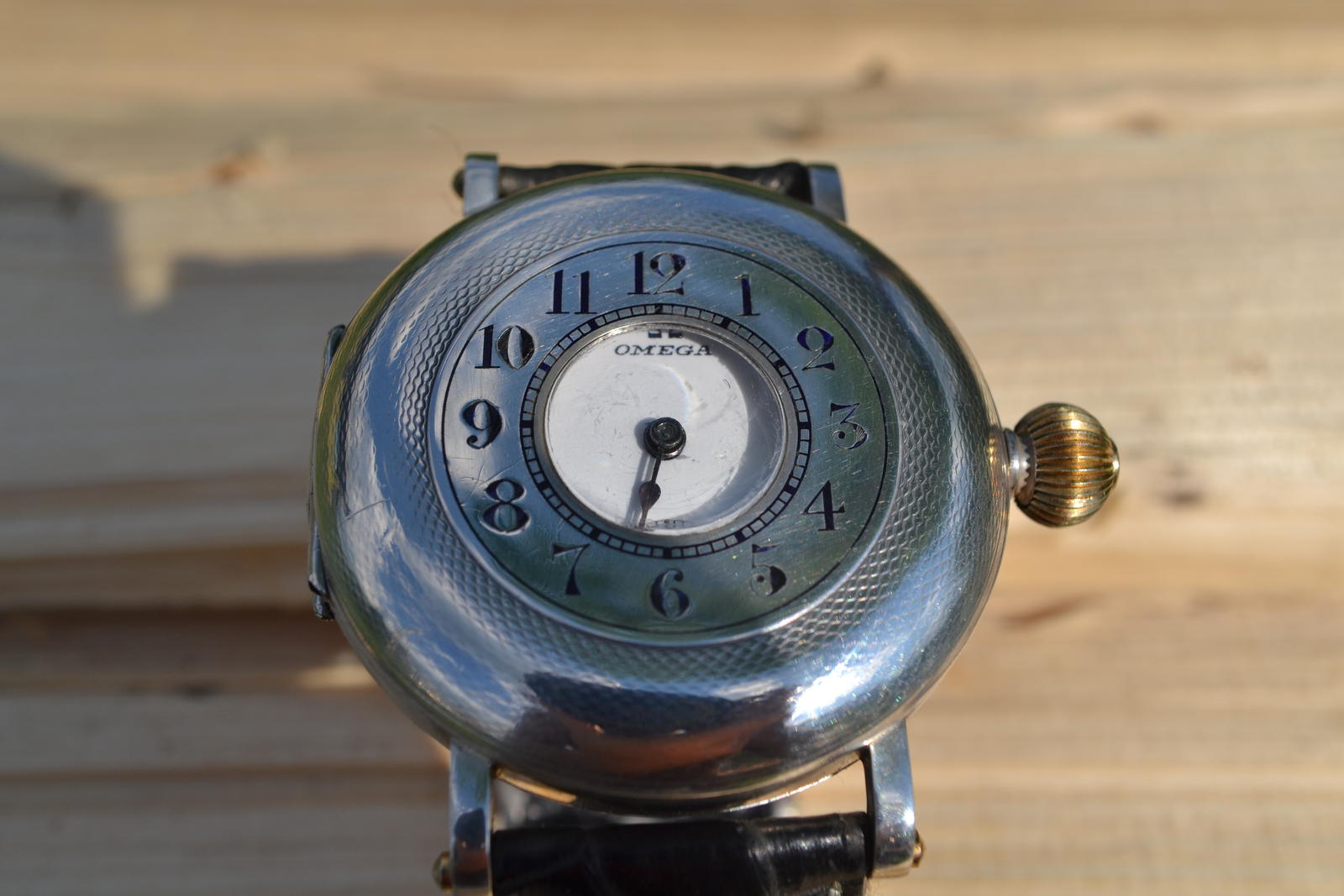Vintage Omega half-hunter pocket watch converted to wristwatch on black leather strap — front view